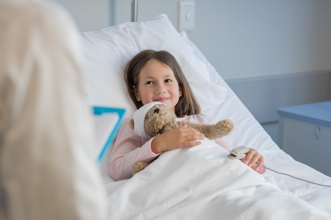 Girl in hospital bed with teddy bear